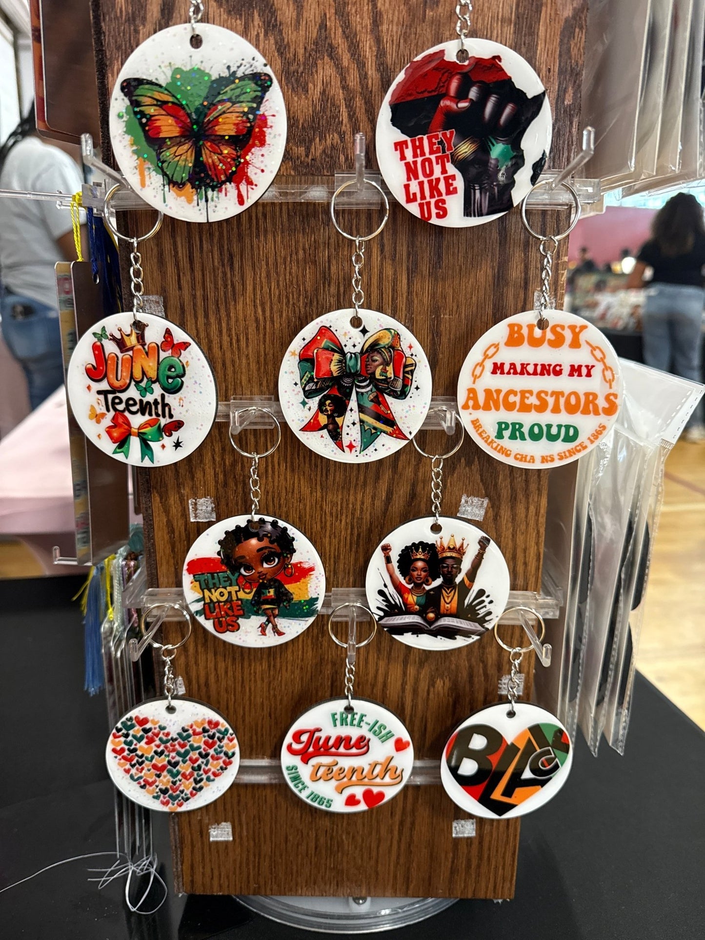 Collection of keychains with various designs on a wooden stand.