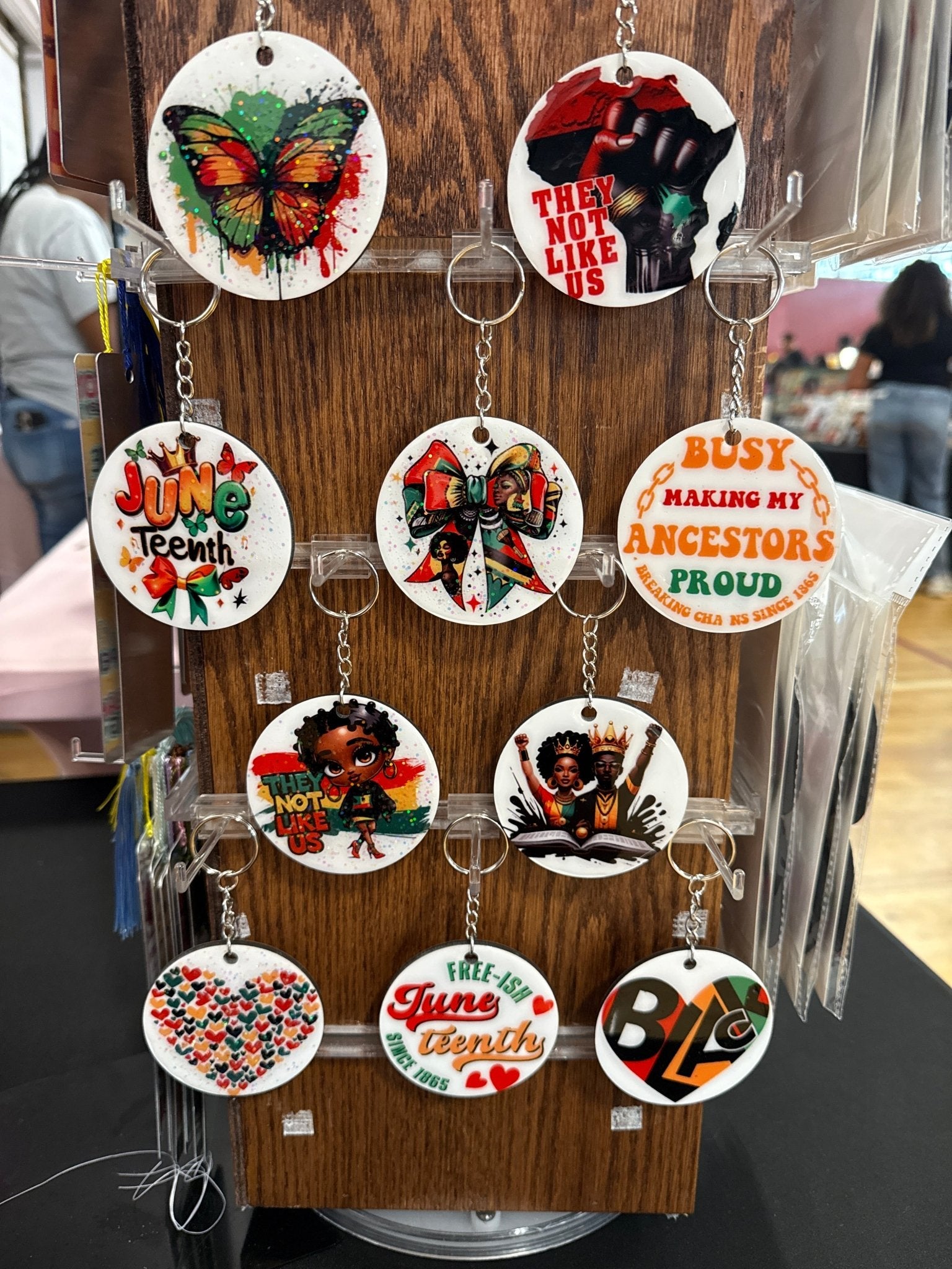 Collection of keychains with various designs on a wooden stand.